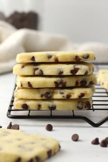 A stack of chocolate chip shortbread cookies on a cooling rack.