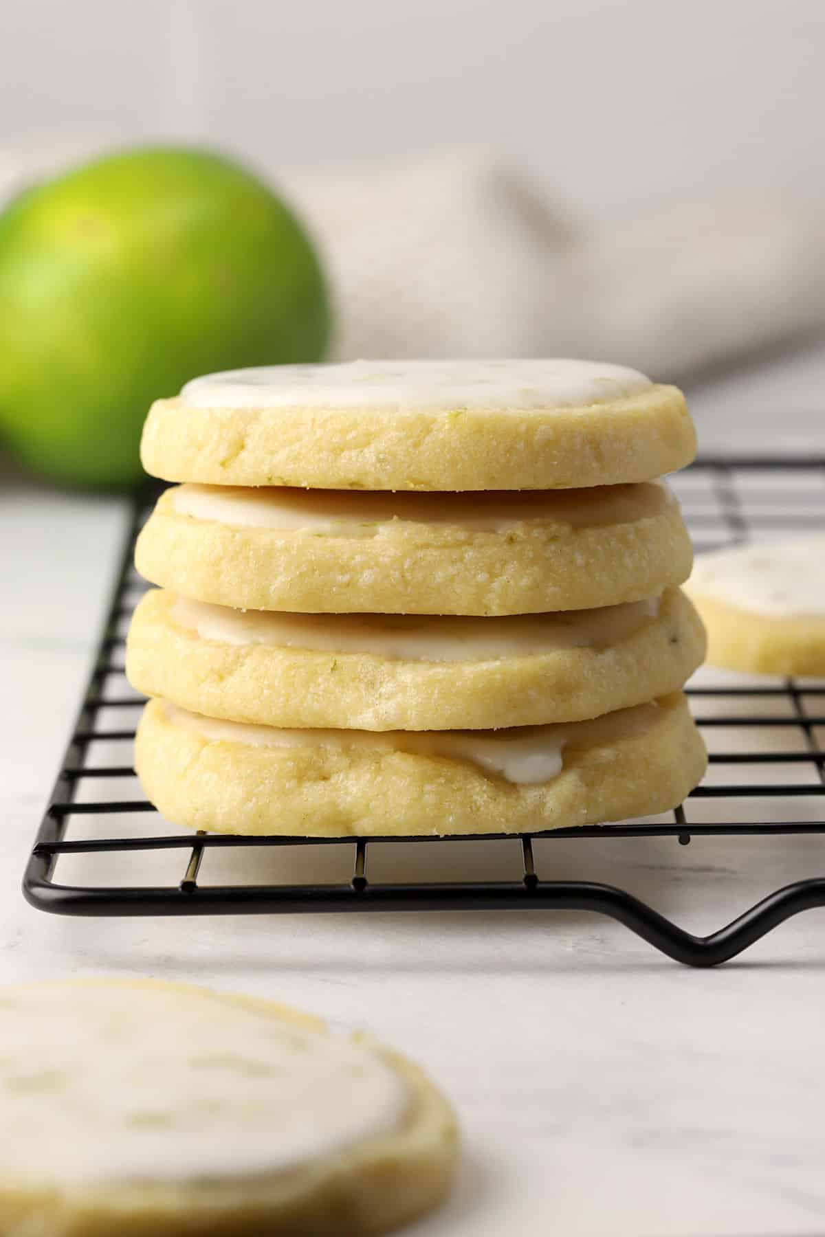 Lime shortbread cookies stacked on a cooling rack.