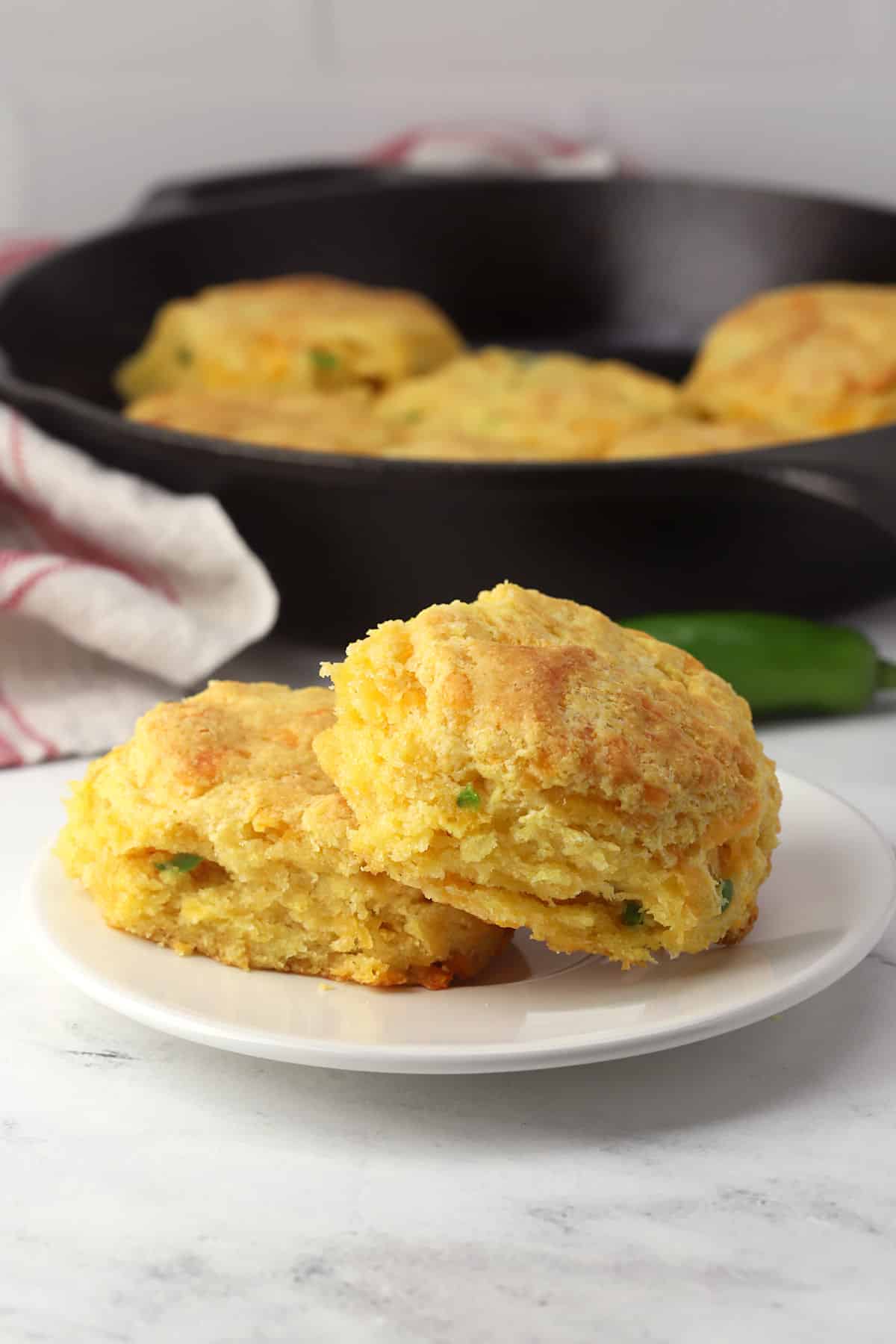 A small plate with two jalapeno cheddar cornmeal biscuits.