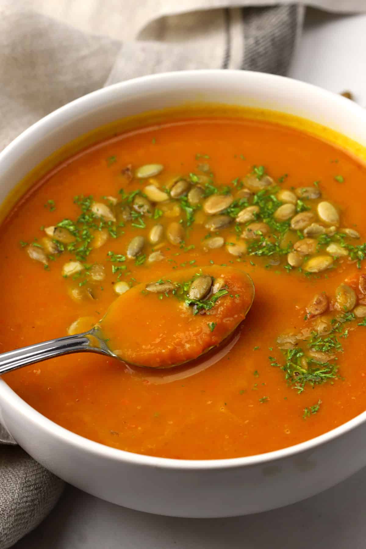Close up of a spoon on a bowl of pumpkin carrot soup.