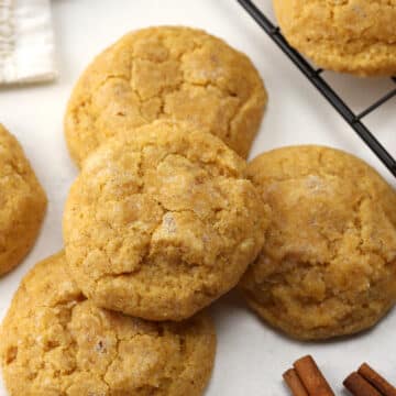 Pumpkin sugar cookies stacked on a counter top.