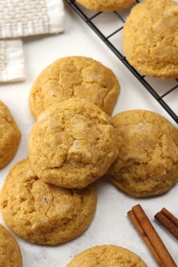 Pumpkin sugar cookies stacked on a counter top.