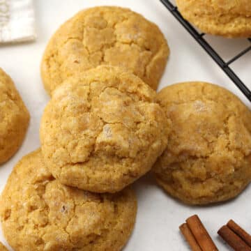 Pumpkin sugar cookies stacked on a counter top.