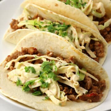 Closeup of Thai pork taco topped with slaw on a plate.