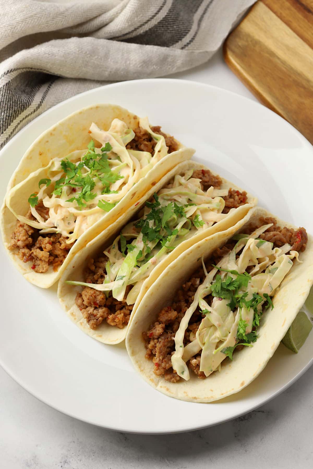 Three Thai pork tacos on a white serving plate.