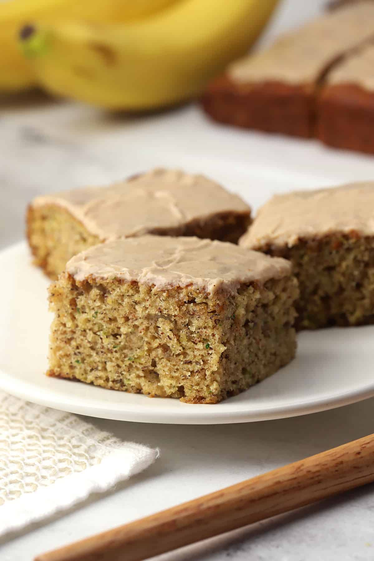 Zucchini banana bread bars sliced into squares on a small white plate.