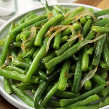Green beans and onions on a round plate.