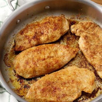 Seared chicken breasts in a pan.