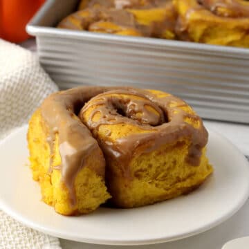 A pumpkin chai cinnamon roll on a small plate.