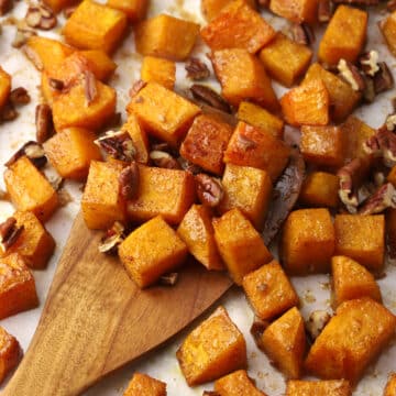 Roasted butternut squash being scooped with a wooden spatula.