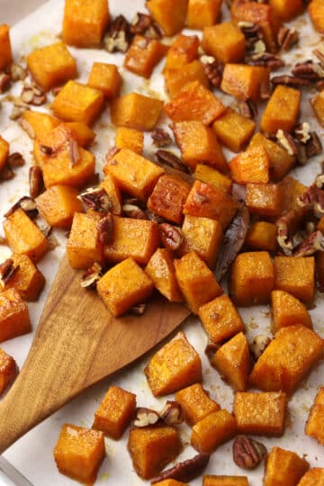 Roasted butternut squash being scooped with a wooden spatula.