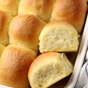 Two dinner rolls displayed with others in a baking pan.