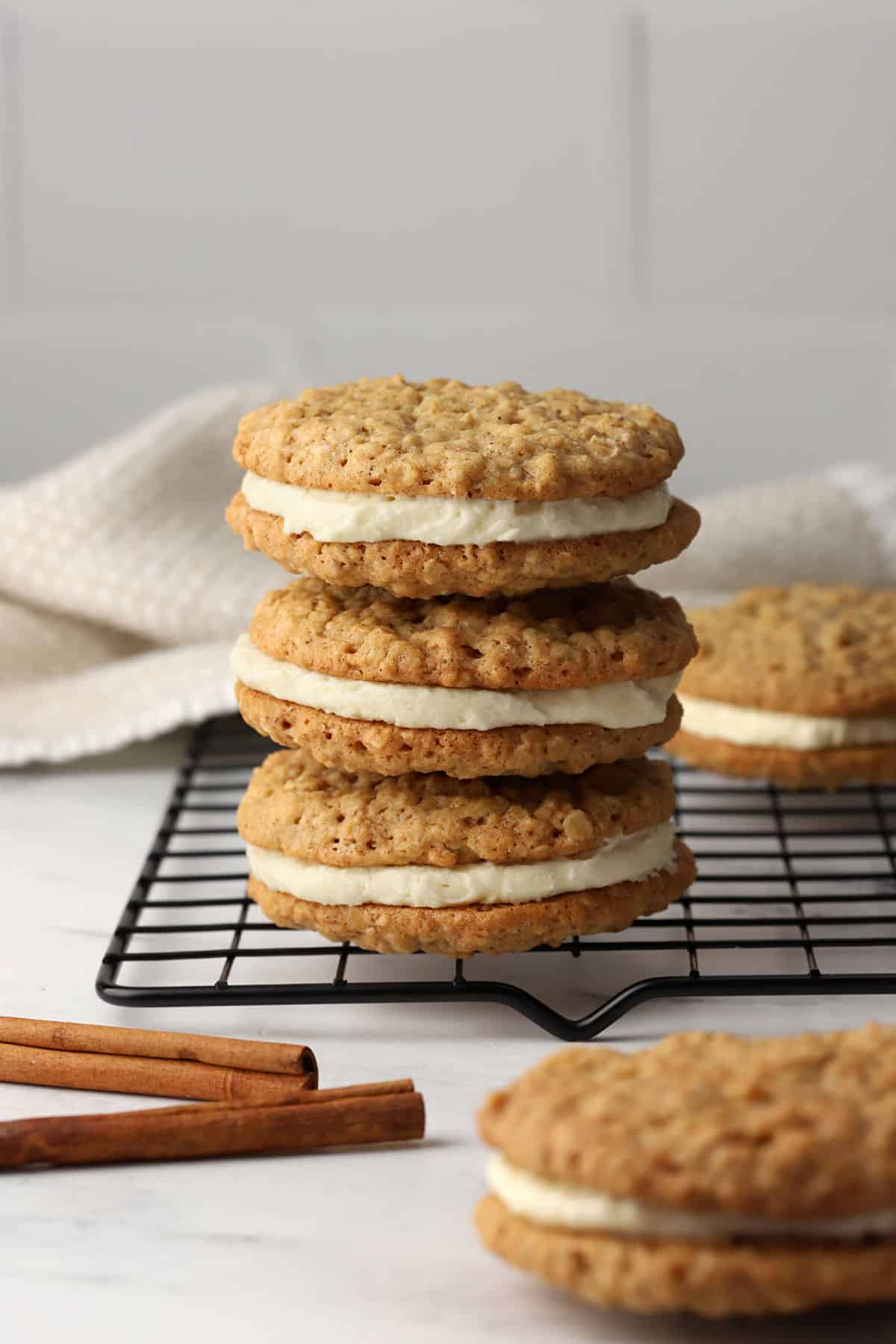 A stack of oatmeal cookie sandwiches on a cooling rack.