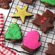 Chocolate cut out cookies on a cooling rack with festive icing.