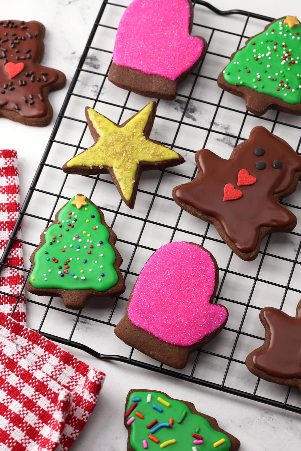 Chocolate cut out cookies on a cooling rack with festive icing.