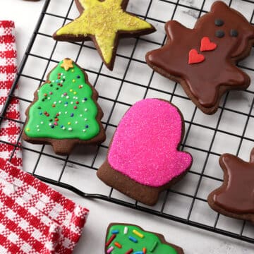 Chocolate cut out cookies on a cooling rack with festive icing.