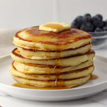 A stack of pancakes with butter and syrup on top.
