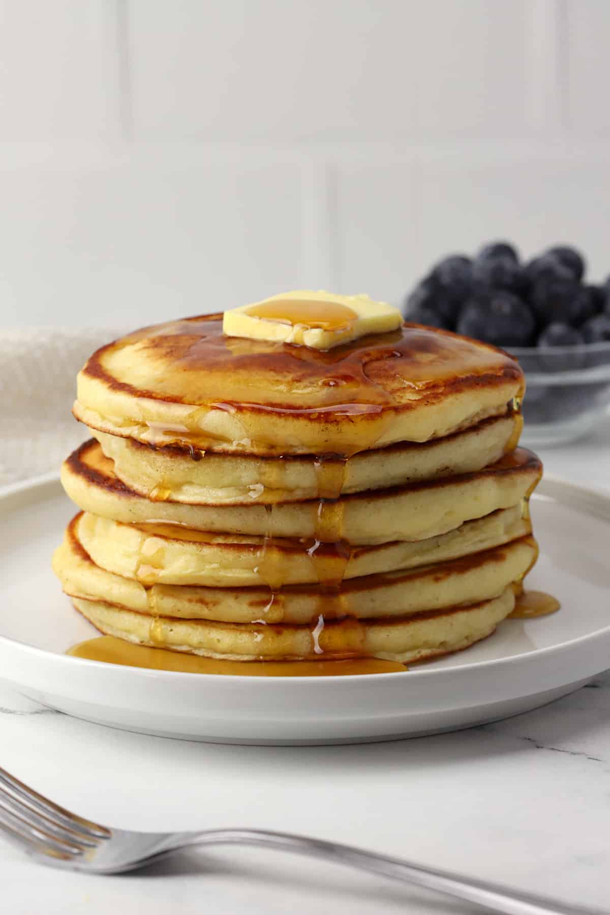 A stack of pancakes with butter and syrup on top.