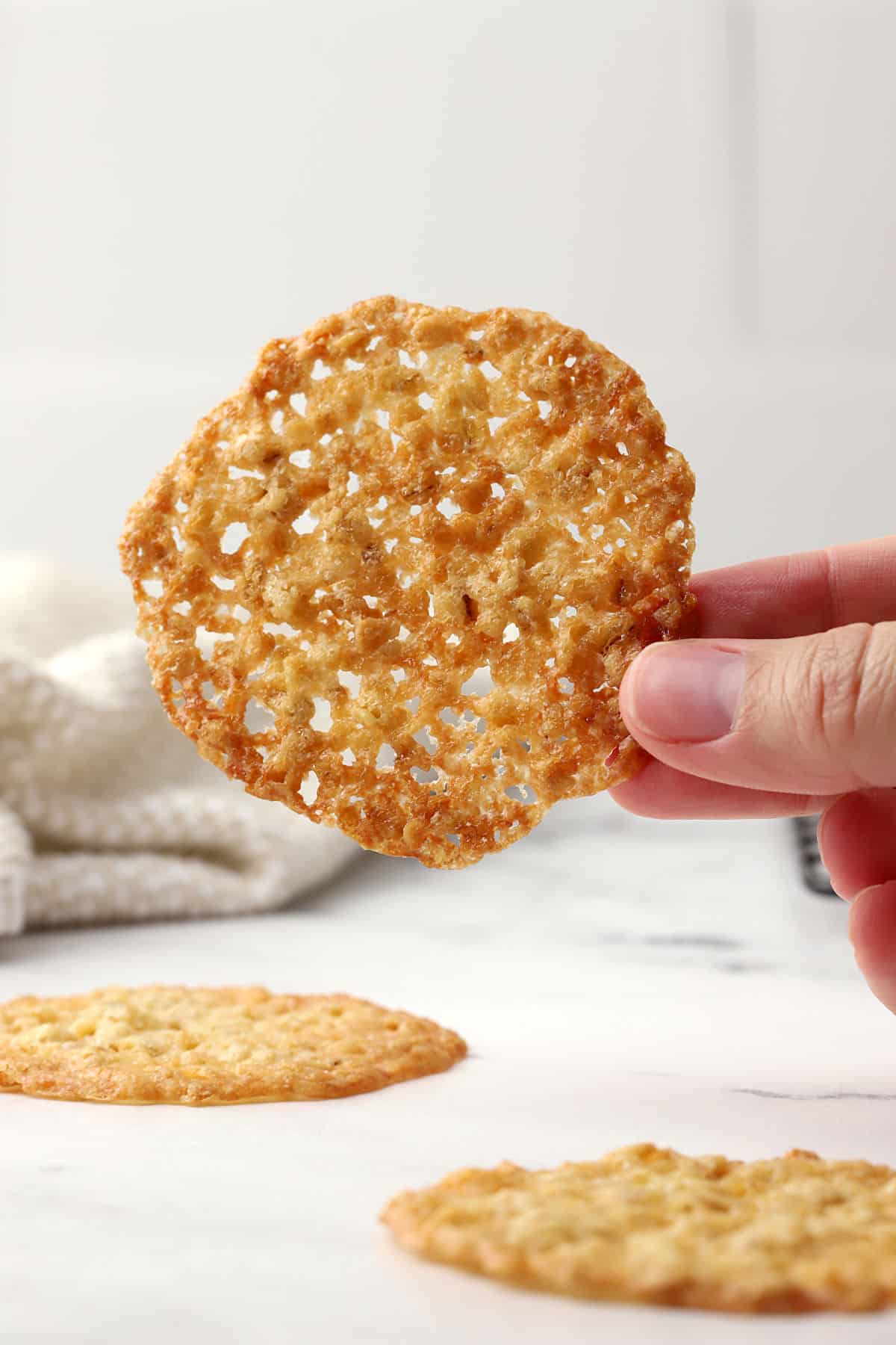 A lace cookie held to show out thin and crisp it is.