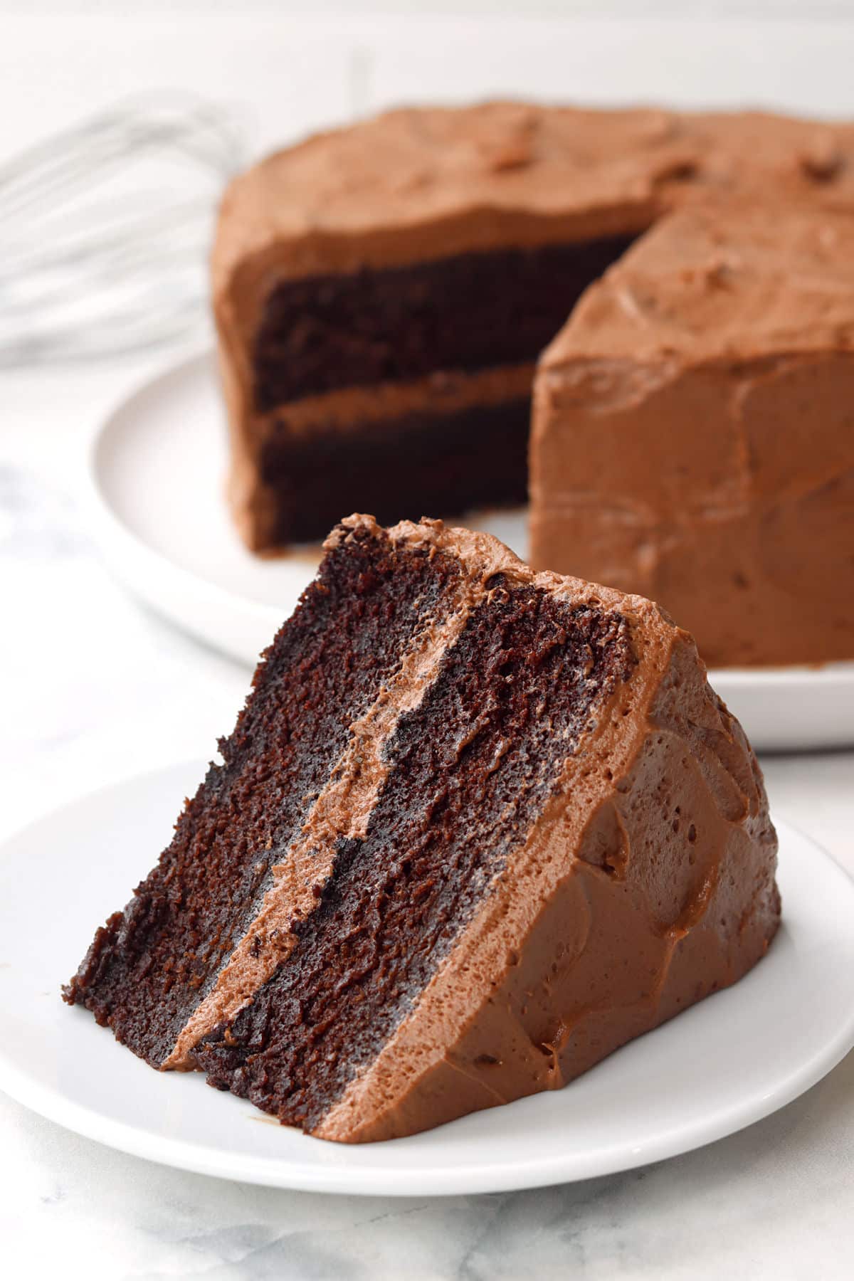 A slice of chocolate layer cake on a white plate.