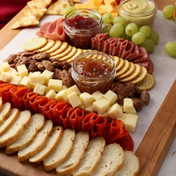 Charcuterie board arranged on a wooden cutting board in a tree shape.