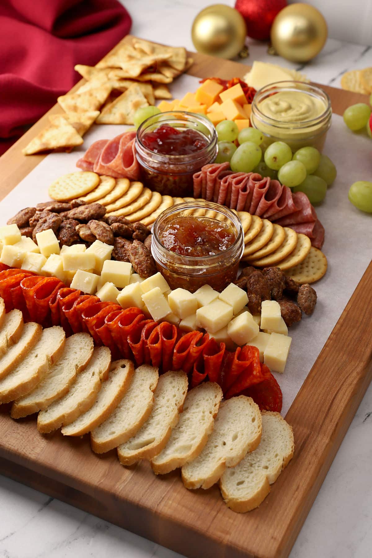 Charcuterie board arranged on a wooden cutting board in a tree shape.