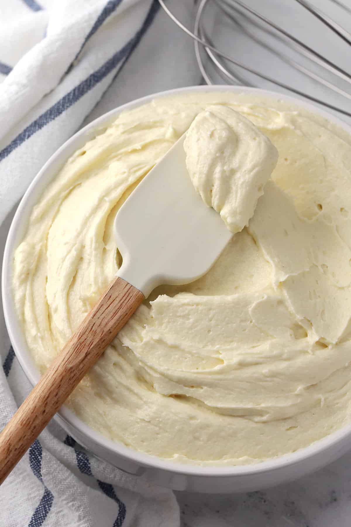 A bowl of ermine frosting with a wooden spatula.