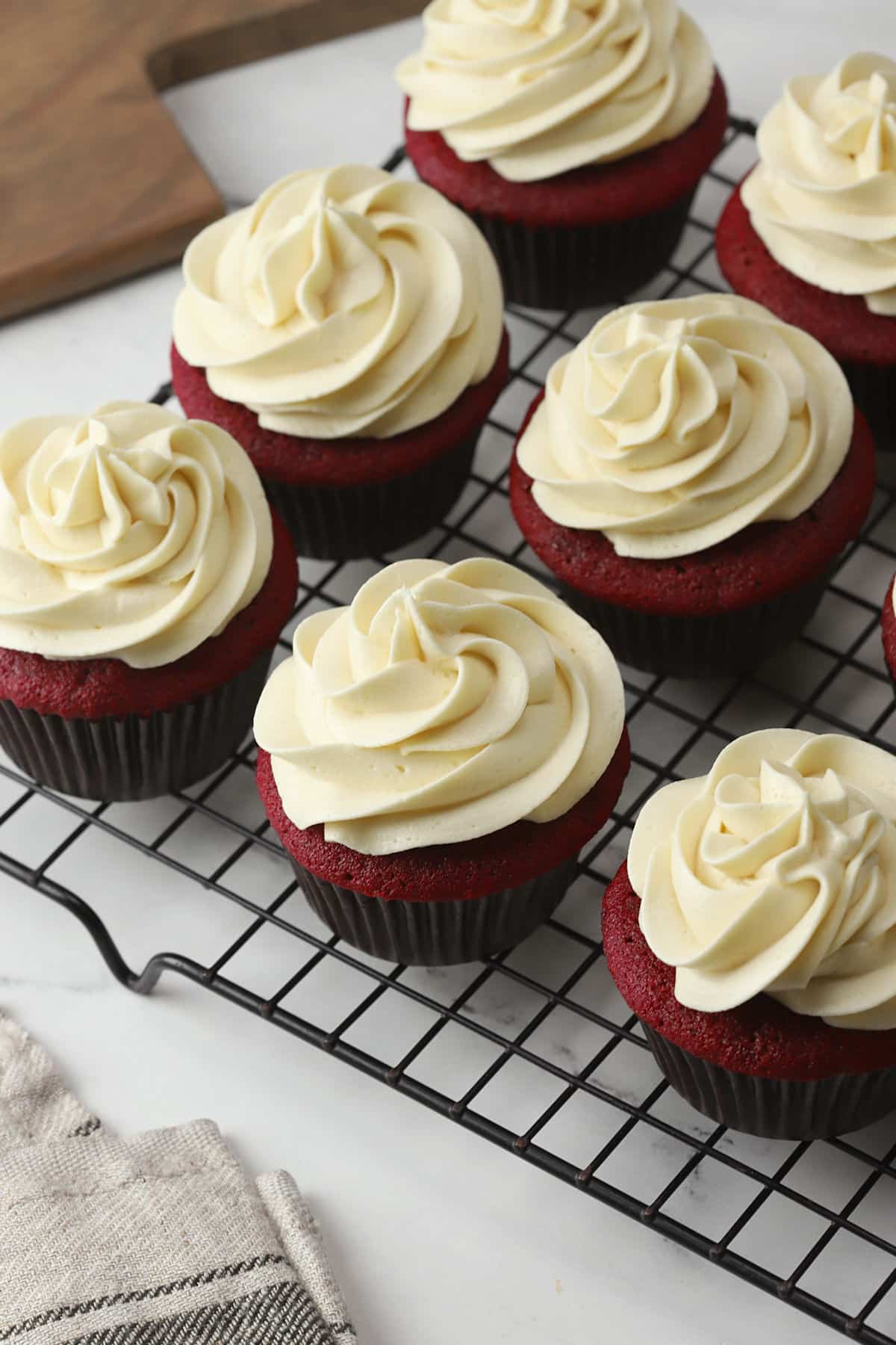 A batch of red velvet cupcakes on a cooling rack.