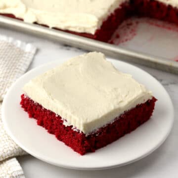 A slice of frosted red velvet cake.