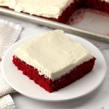 A slice of frosted red velvet cake.
