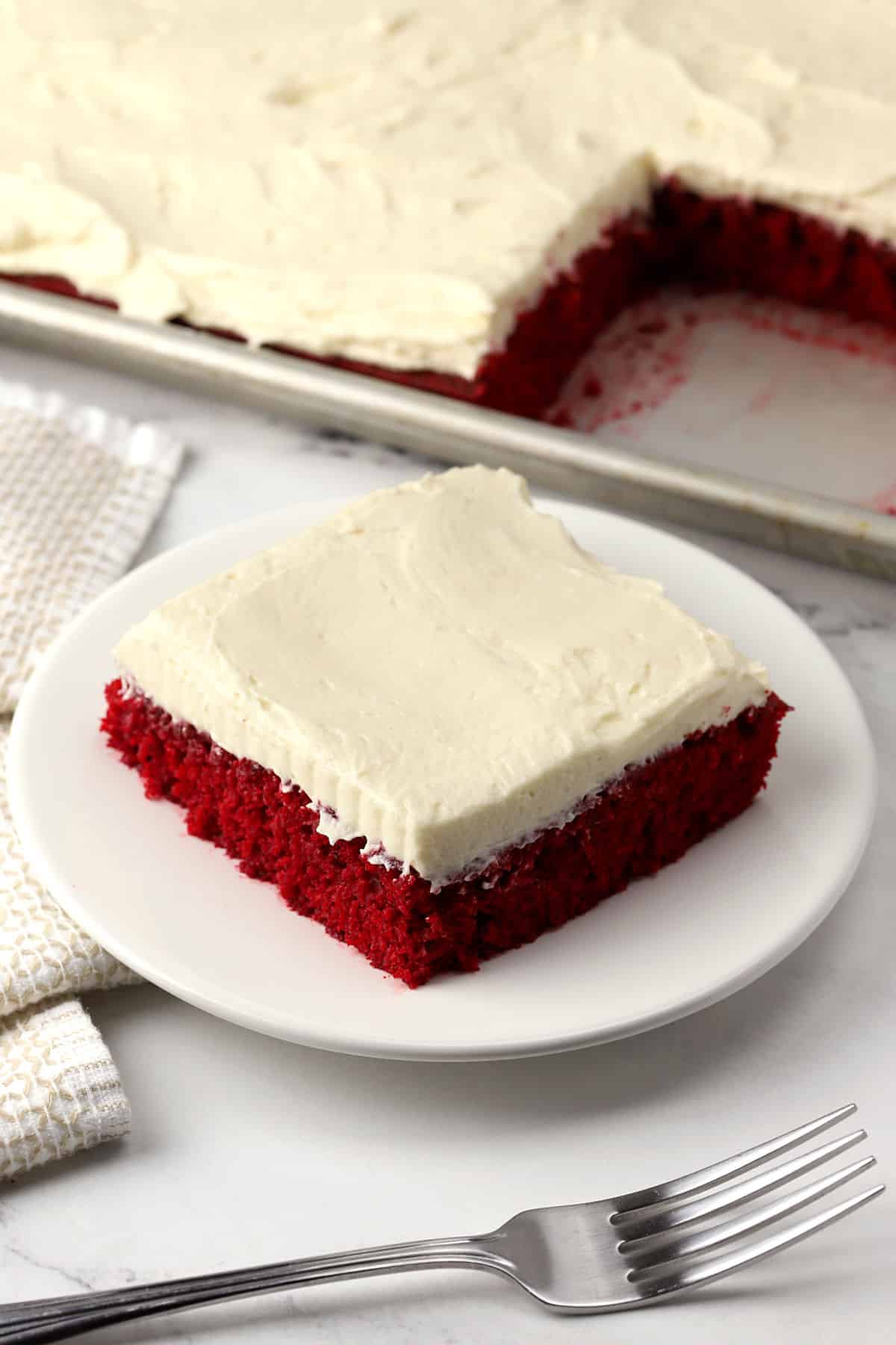A slice of frosted red velvet cake.