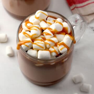 Mug of hot chocolate with marshmallows and caramel sauce on top.