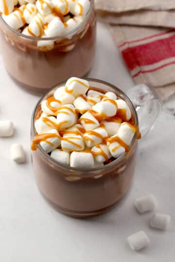 Mug of hot chocolate with marshmallows and caramel sauce on top.