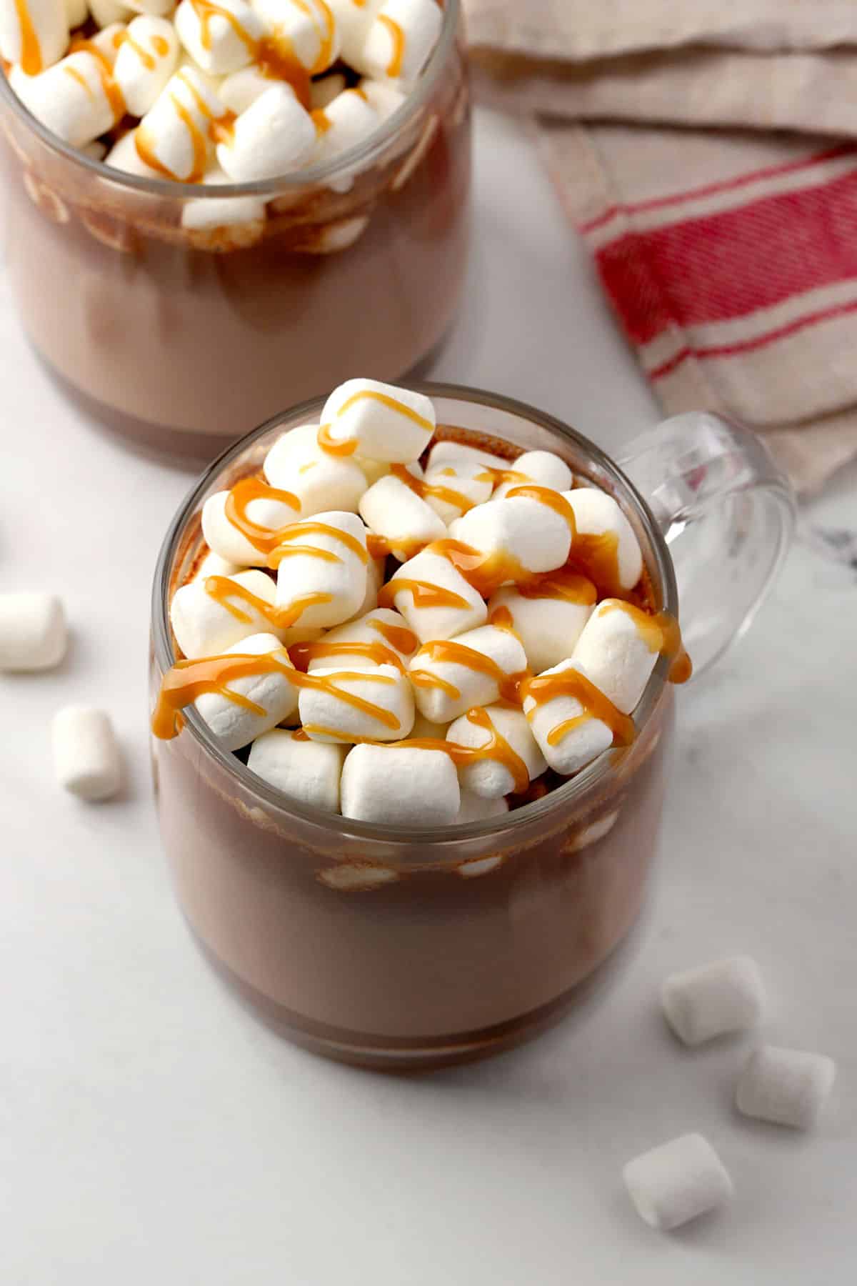 Mug of hot chocolate with marshmallows and caramel sauce on top.