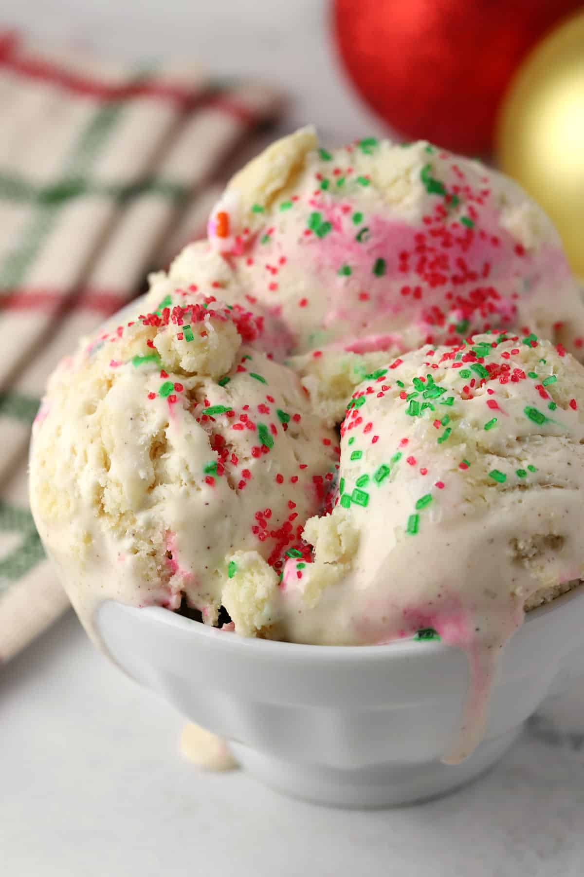 Close up view of Christmas cookie ice cream in a bowl with red and green sprinkles on top.