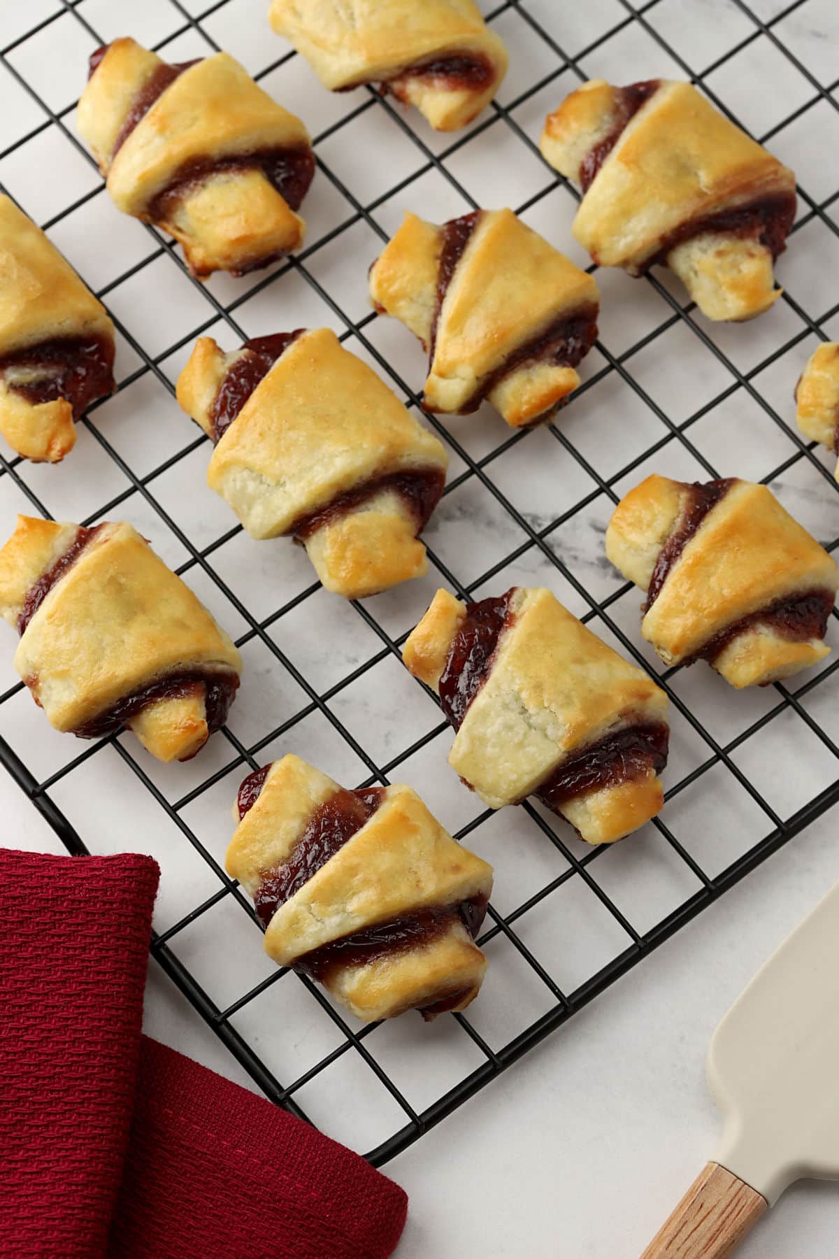 Overhead view of raspberry rugelach pastries on a cooling rack.