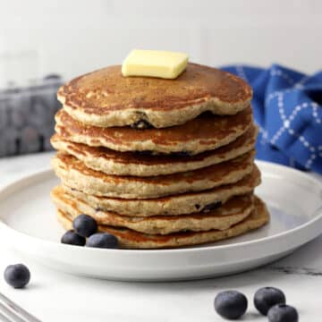 A stack of blueberry oat pancakes on a white plate.