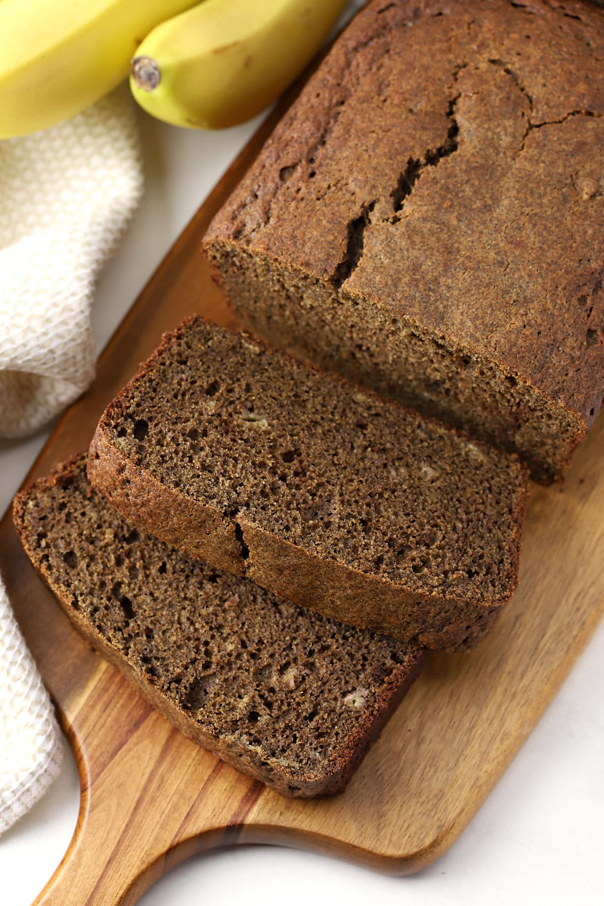 A sliced loaf of buckwheat banana bread on a cutting board.