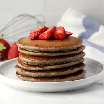A stack of pancakes with strawberries on top.