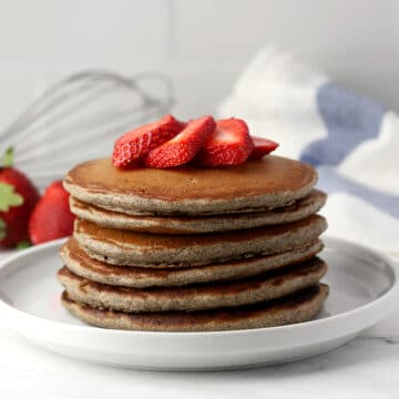 A stack of pancakes with strawberries on top.