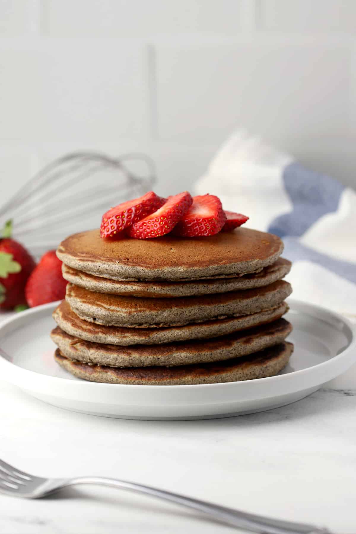 A stack of pancakes with strawberries on top.