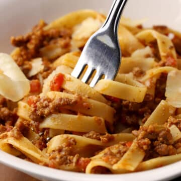 A fork twirling fettuccine with bolognese.