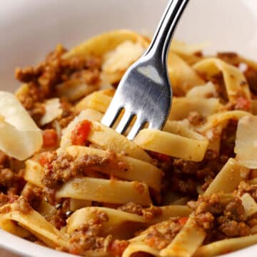 A fork twirling fettuccine with bolognese.
