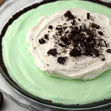 A grasshopper pie topped with whipped cream and crushed Oreos.