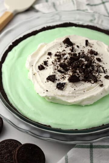 A grasshopper pie topped with whipped cream and crushed Oreos.