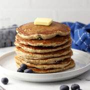 A stack of blueberry oat pancakes on a white plate.