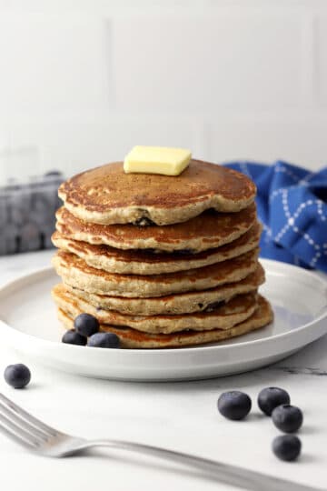 A stack of blueberry oat pancakes on a white plate.