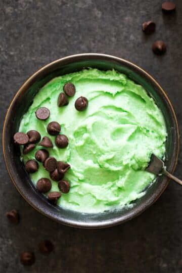 A bowl of mint frosting decorated with chocolate chips.