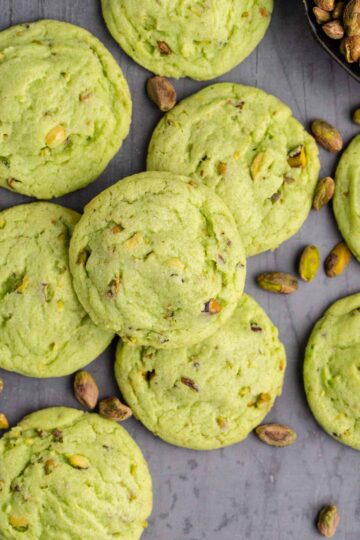 A stack of pistachio cookies on a cutting board.
