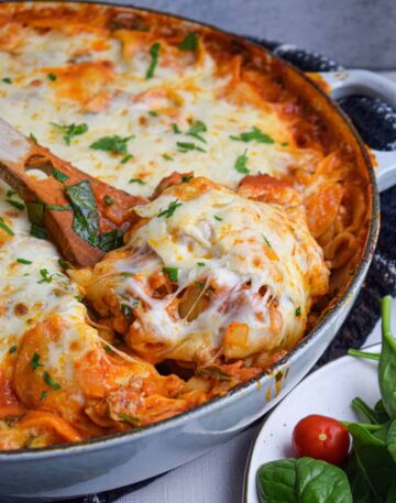 A pan of cheesy tortellini with a wooden serving spoon.